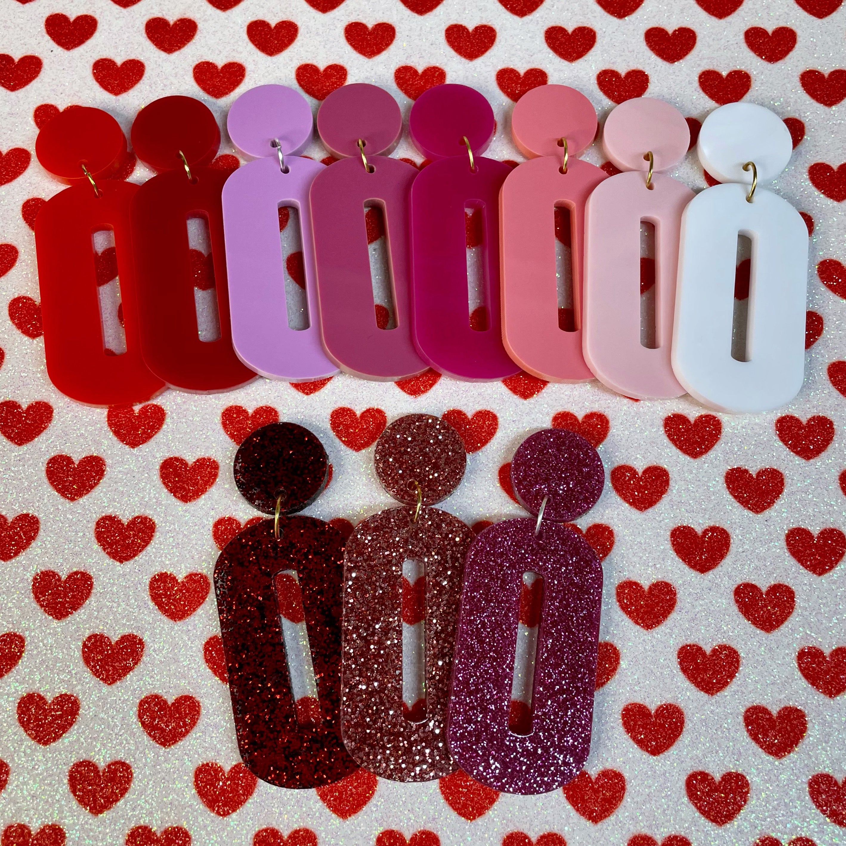 A pair of stylish oval drop earrings made from laser-cut acrylic, showcasing their elegant design and available colors.