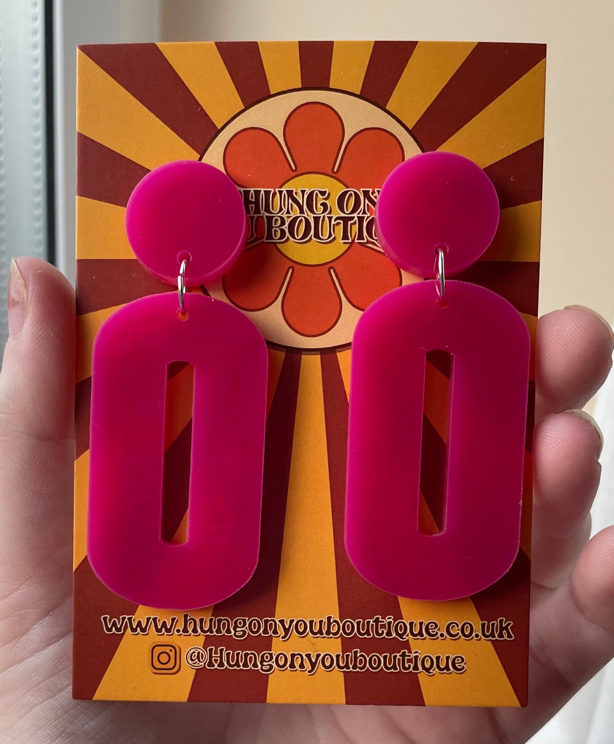 A pair of stylish oval drop earrings made from laser-cut acrylic, showcasing their elegant design and available colors.