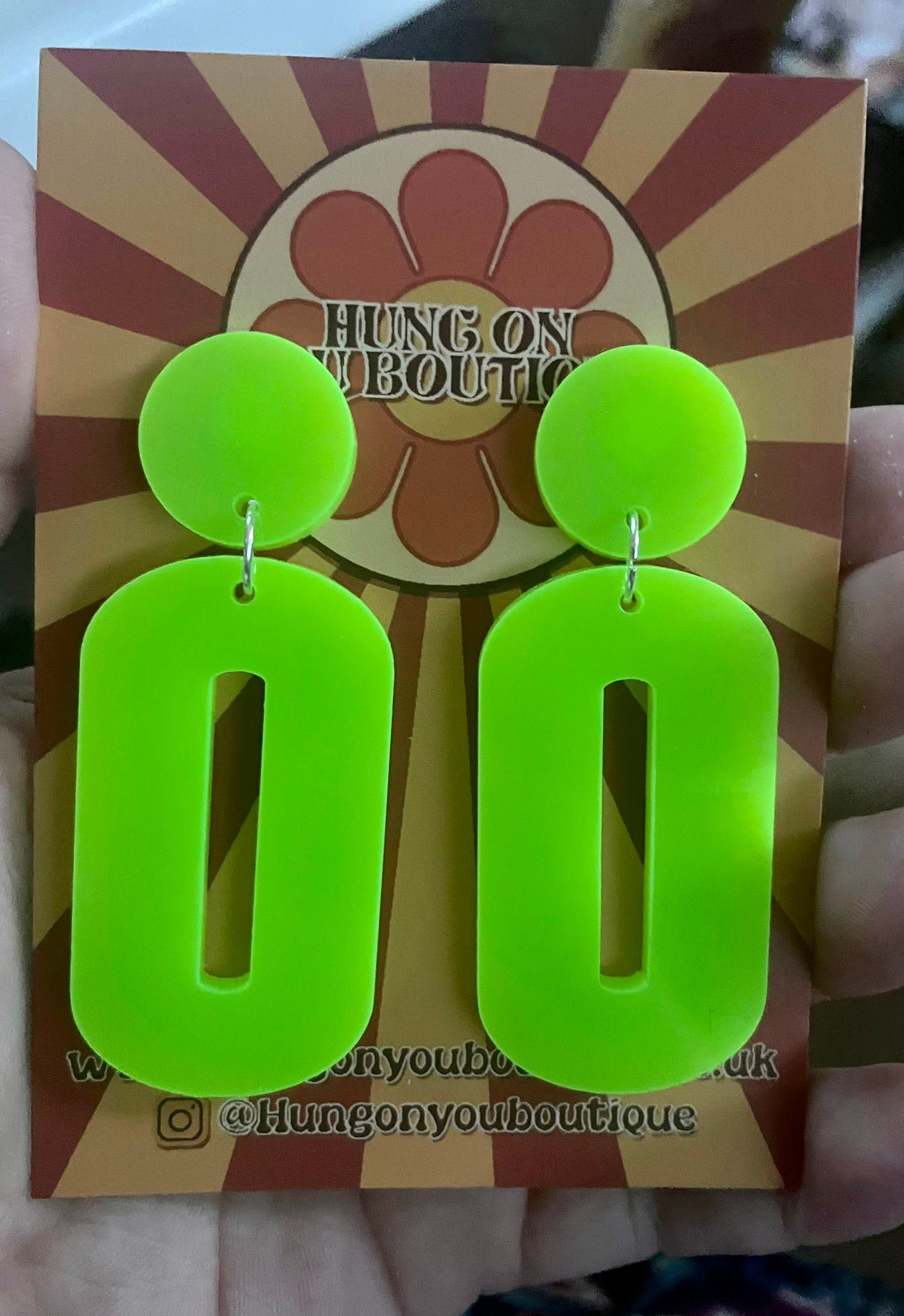 A pair of stylish oval drop earrings made from laser-cut acrylic, showcasing their elegant design and available colors.