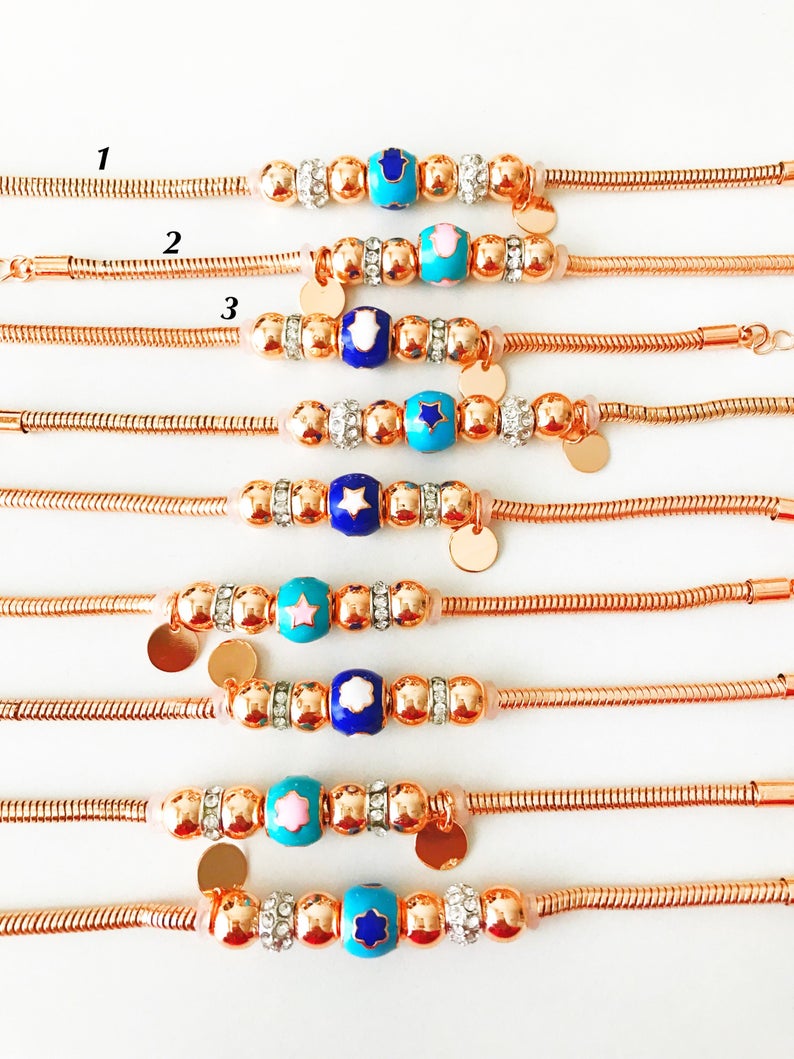 A beautiful rose gold Pandora charm bracelet featuring various charms including a hamsa hand, four-leaf clover, and star, made from tarnish-resistant stainless steel.