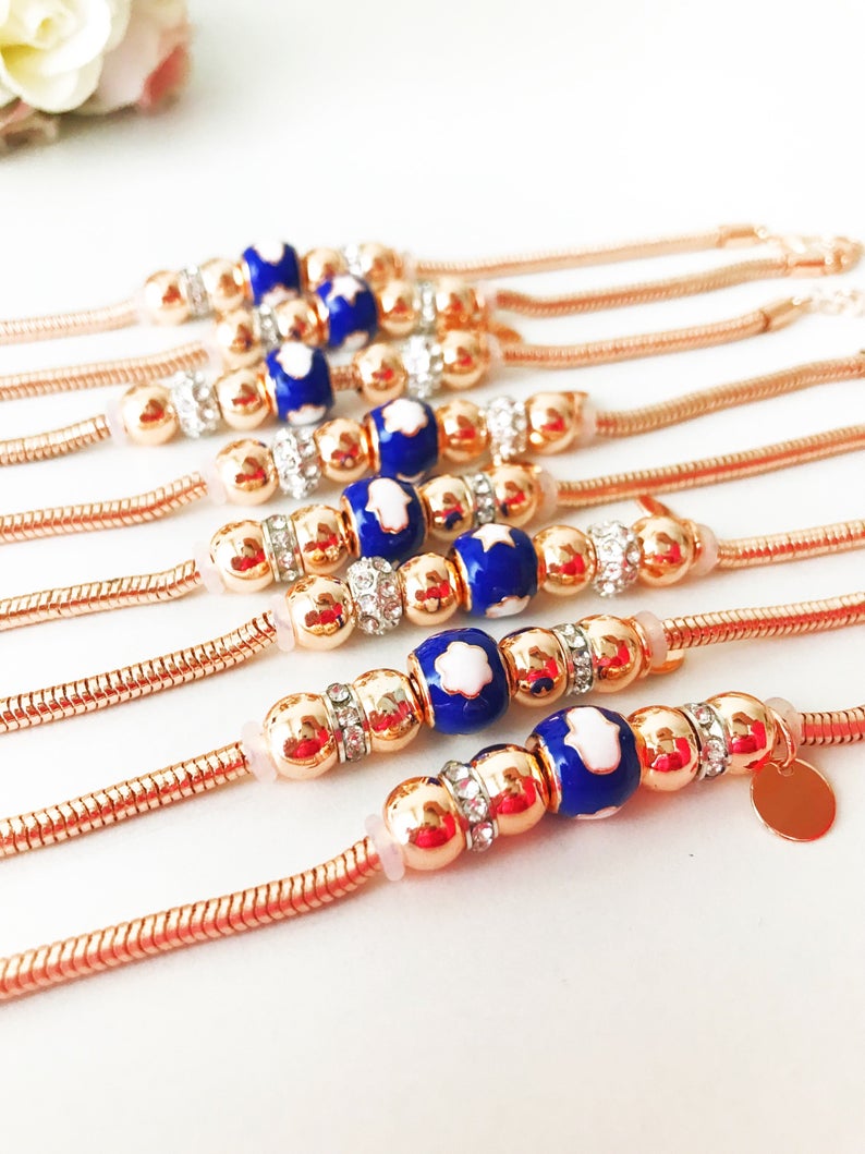 A beautiful rose gold Pandora charm bracelet featuring various charms including a hamsa hand, four-leaf clover, and star, made from tarnish-resistant stainless steel.