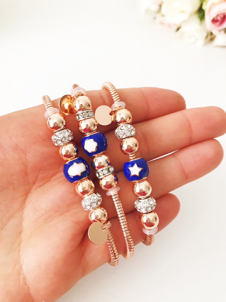 A beautiful rose gold Pandora charm bracelet featuring various charms including a hamsa hand, four-leaf clover, and star, made from tarnish-resistant stainless steel.