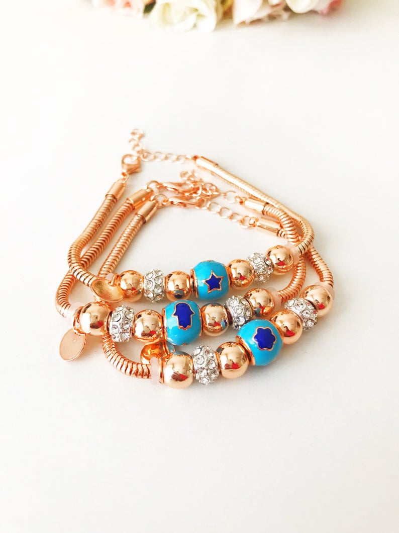 A beautiful rose gold Pandora charm bracelet featuring various charms including a hamsa hand, four-leaf clover, and star, made from tarnish-resistant stainless steel.