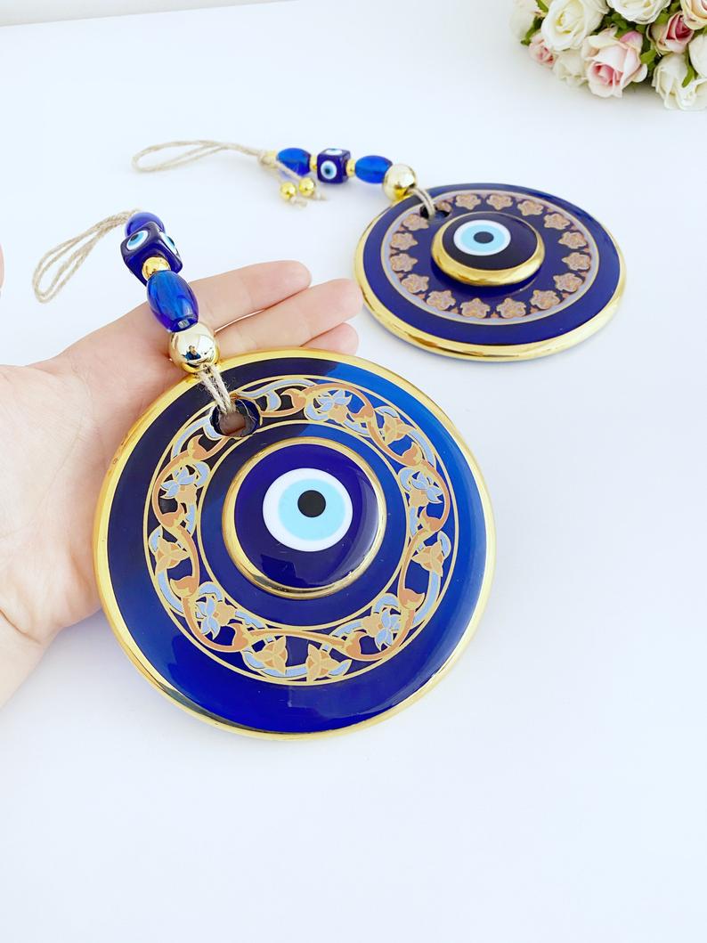 Handmade patterned evil eye wall hanging featuring blue and gold beads, measuring 32cm in length, showcasing intricate mosaic art.