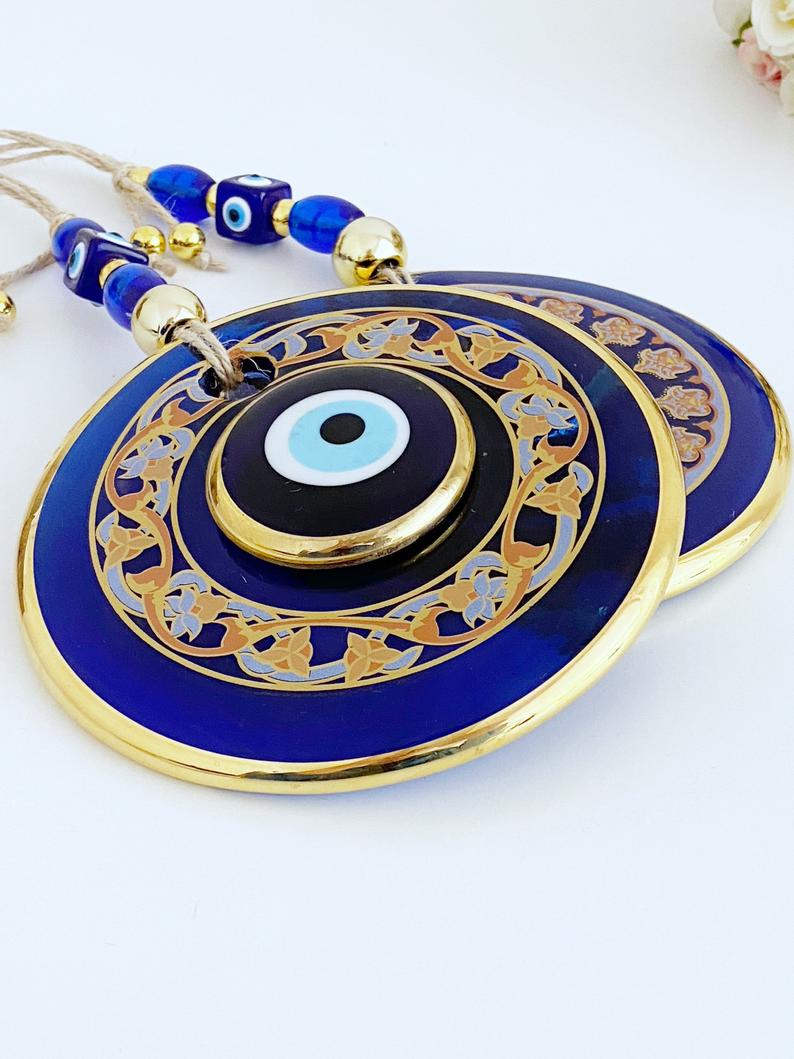 Handmade patterned evil eye wall hanging featuring blue and gold beads, measuring 32cm in length, showcasing intricate mosaic art.