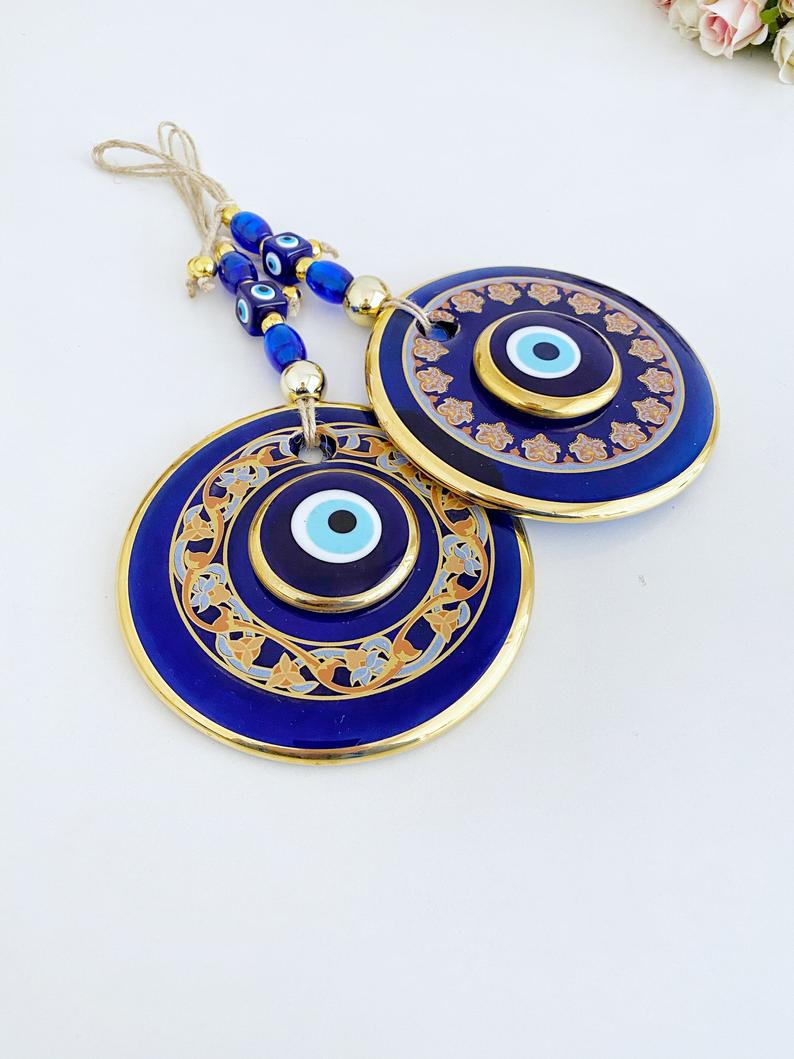 Handmade patterned evil eye wall hanging featuring blue and gold beads, measuring 32cm in length, showcasing intricate mosaic art.