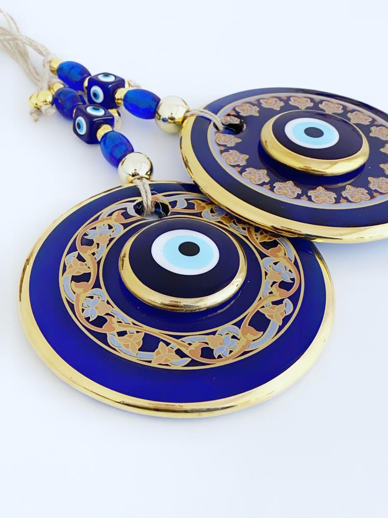 Handmade patterned evil eye wall hanging featuring blue and gold beads, measuring 32cm in length, showcasing intricate mosaic art.