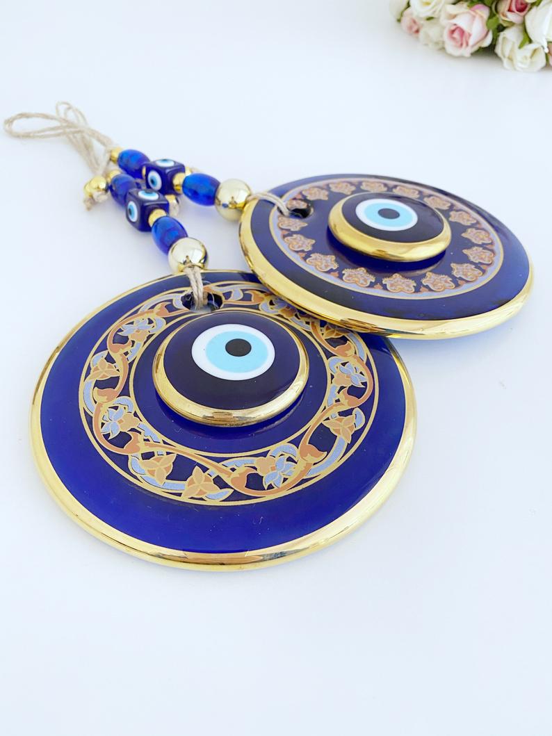 Handmade patterned evil eye wall hanging featuring blue and gold beads, measuring 32cm in length, showcasing intricate mosaic art.