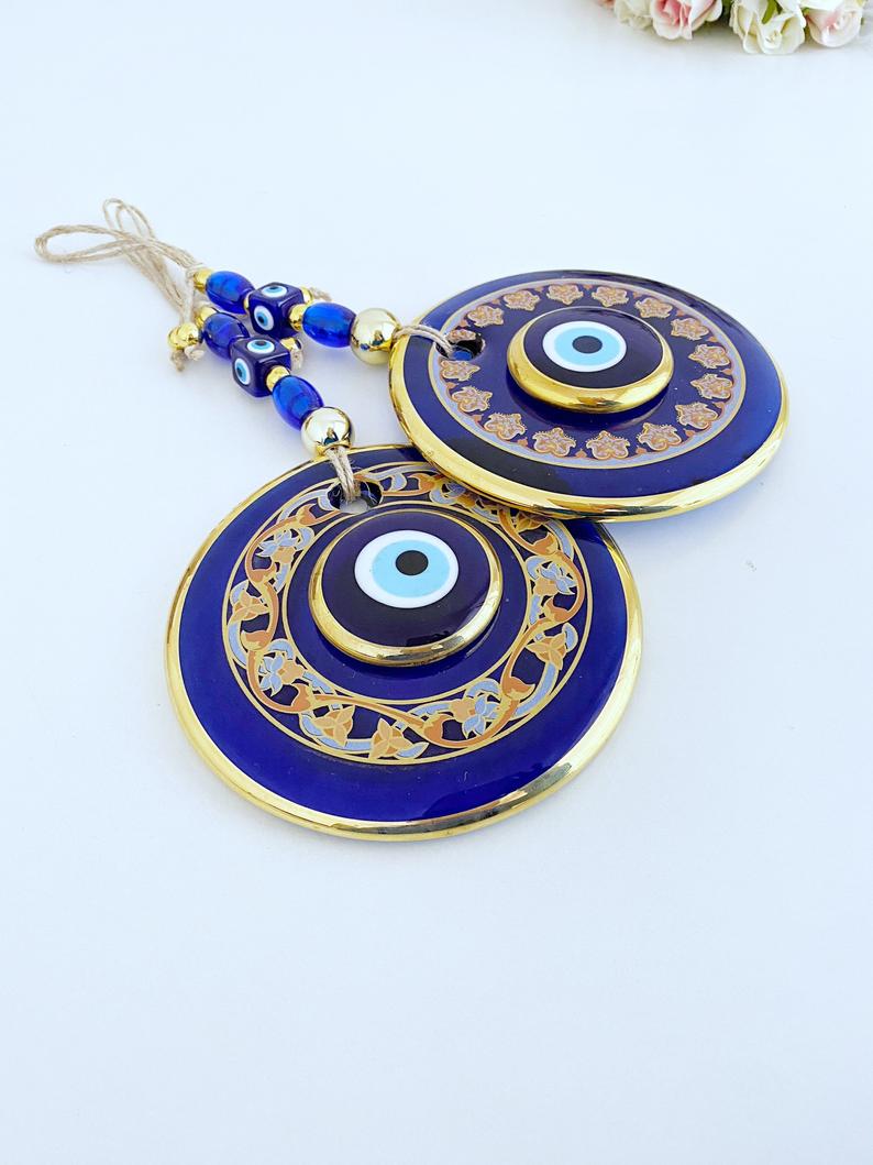 Handmade patterned evil eye wall hanging featuring blue and gold beads, measuring 32cm in length, showcasing intricate mosaic art.