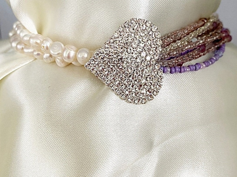 A beautiful Pearl and Lilac Jade Lariat Necklace featuring freshwater pearls, lilac jade, and a faux rhinestone heart button, elegantly displayed.