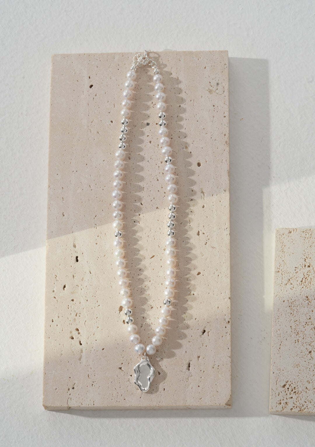Elegant pearl necklace featuring a delicate pendant, handcrafted with natural pearls and sterling silver.