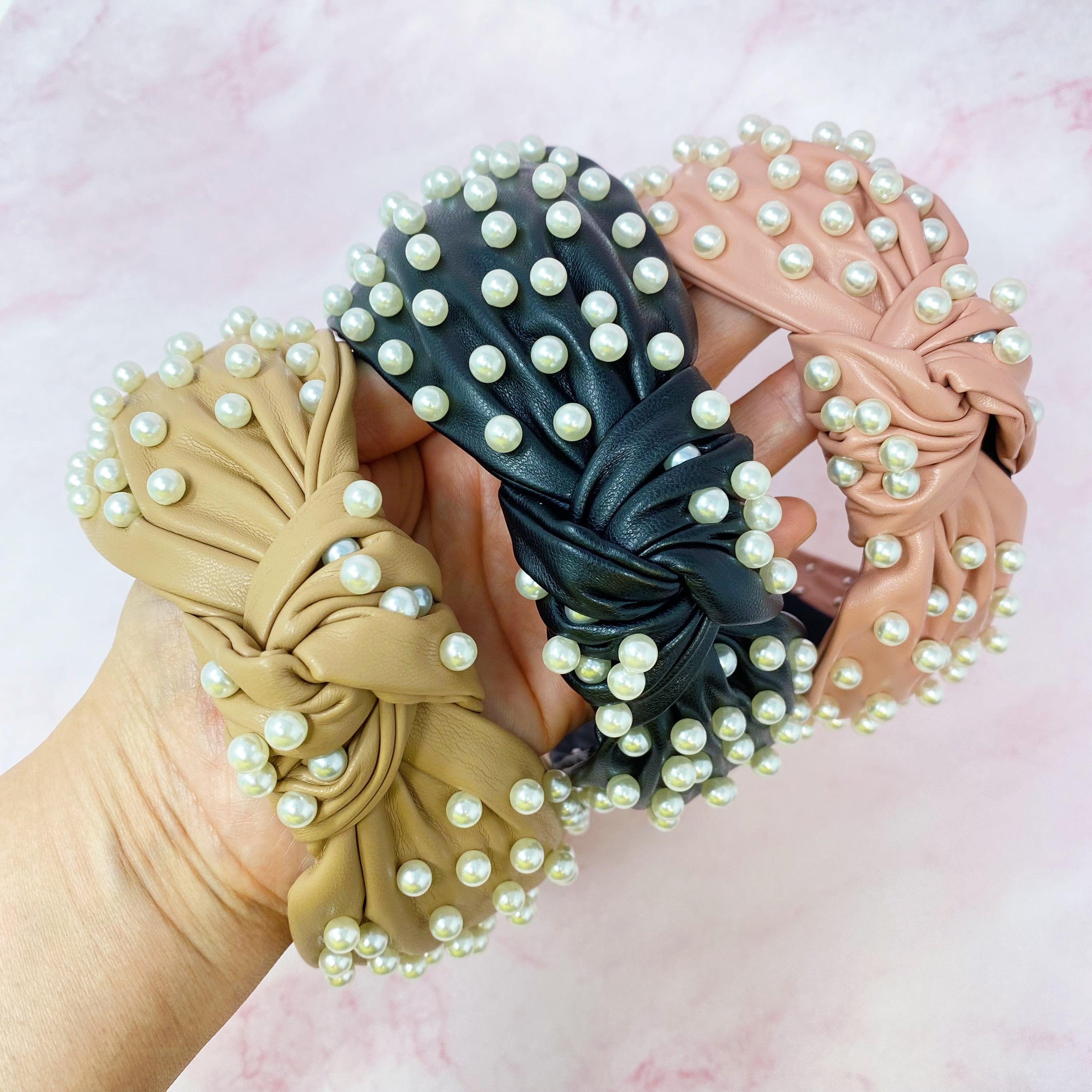 A stylish Pearled Up Vegan Leather Headband featuring soft vegan leather and elegant pearl embellishments in neutral colors.