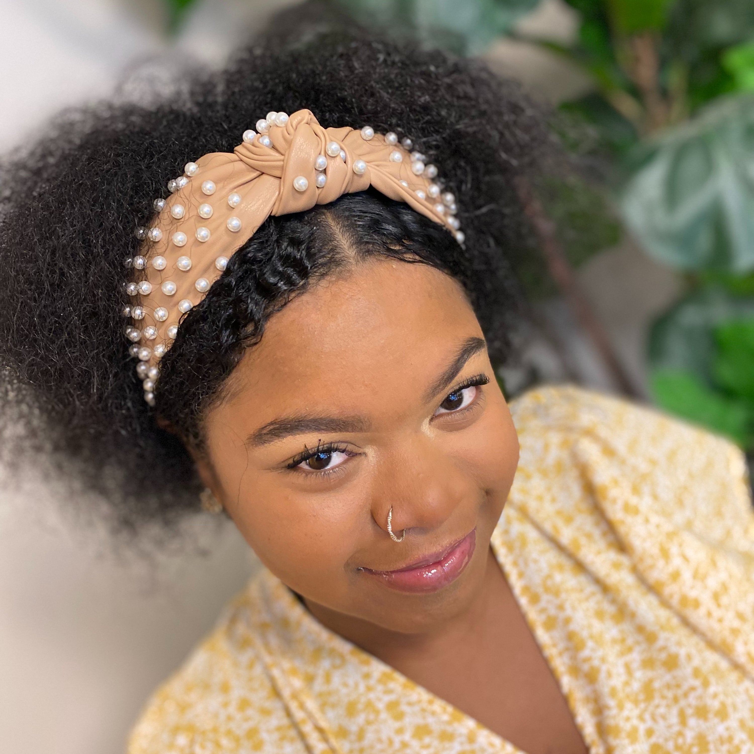 A stylish Pearled Up Vegan Leather Headband featuring soft vegan leather and elegant pearl embellishments in neutral colors.