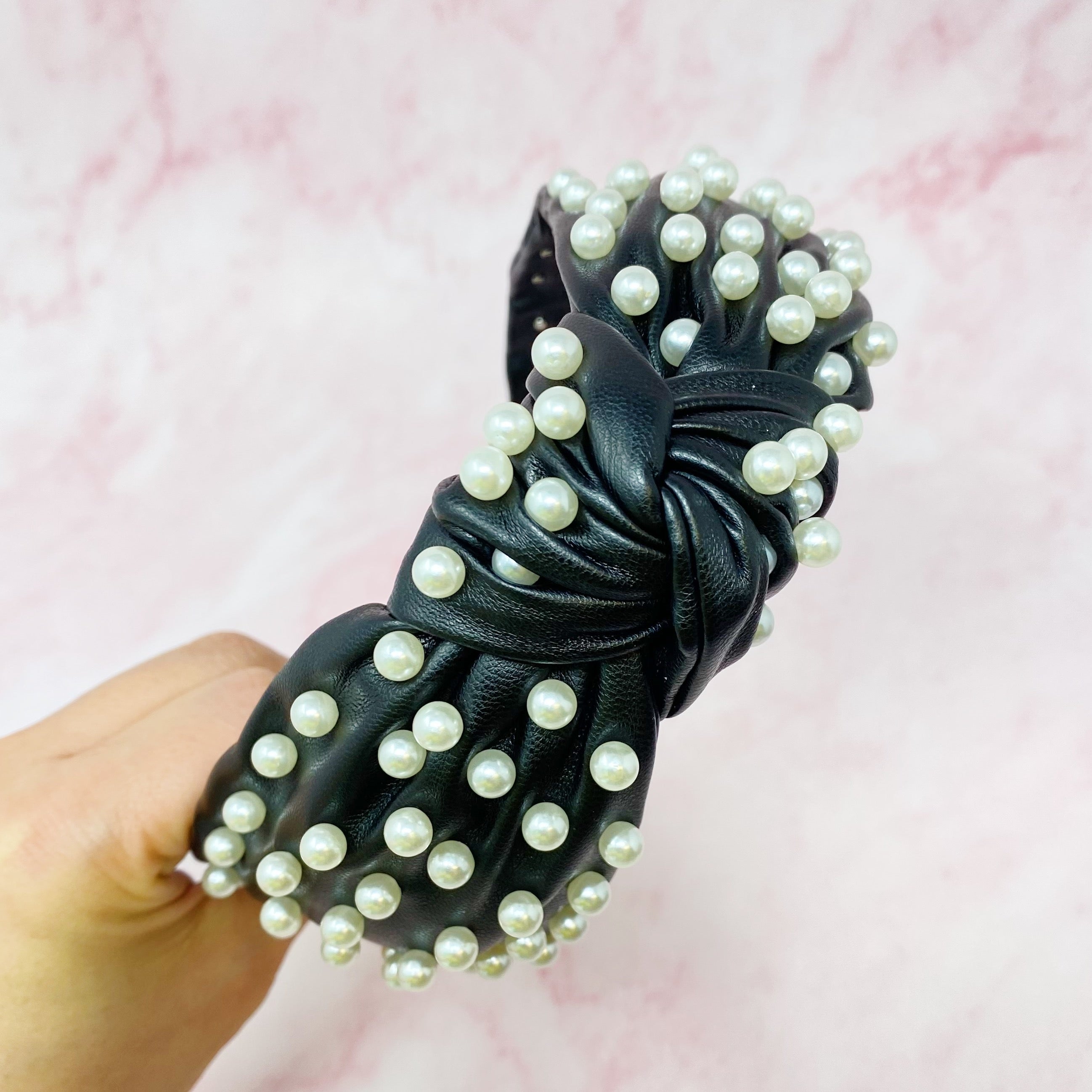 A stylish Pearled Up Vegan Leather Headband featuring soft vegan leather and elegant pearl embellishments in neutral colors.