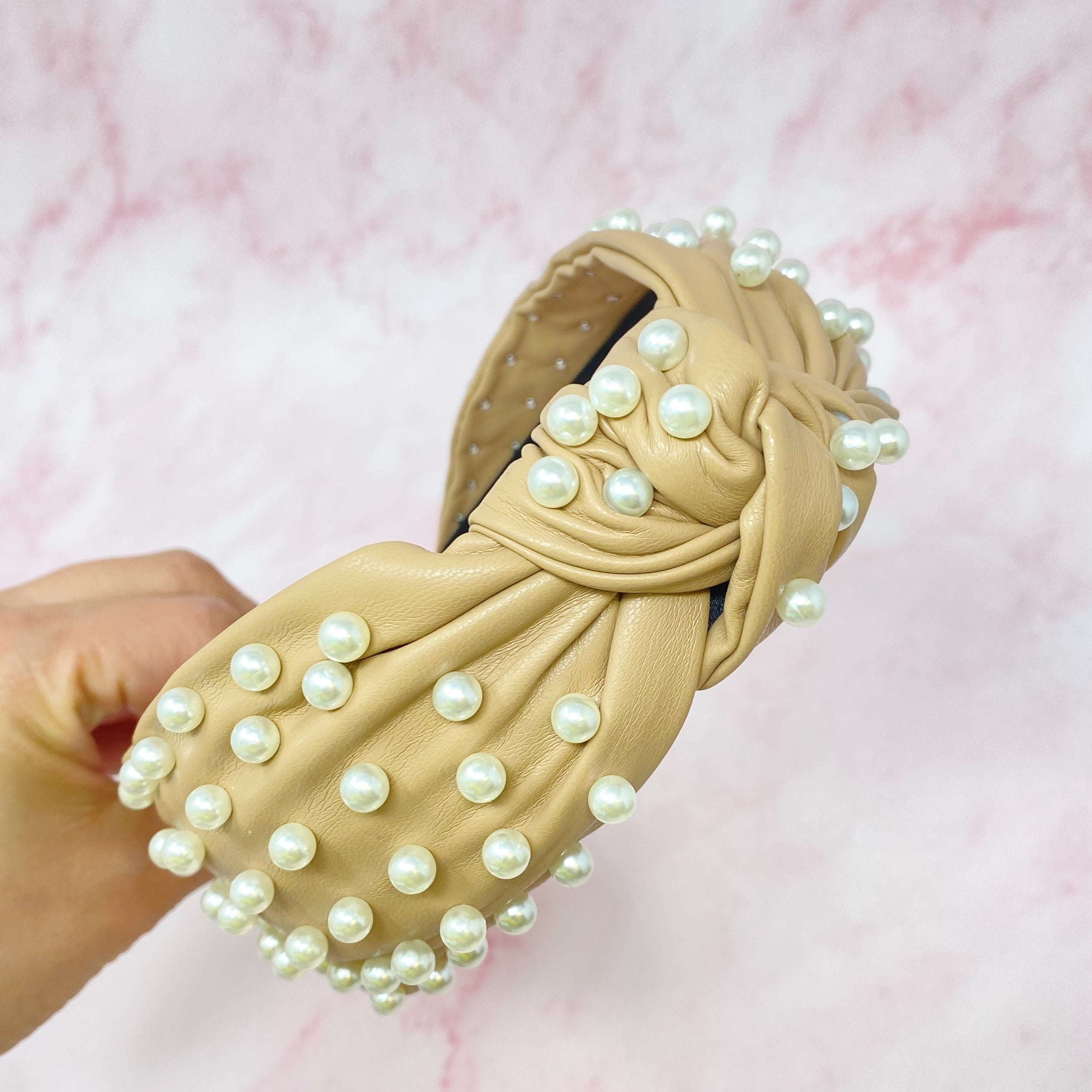 A stylish Pearled Up Vegan Leather Headband featuring soft vegan leather and elegant pearl embellishments in neutral colors.