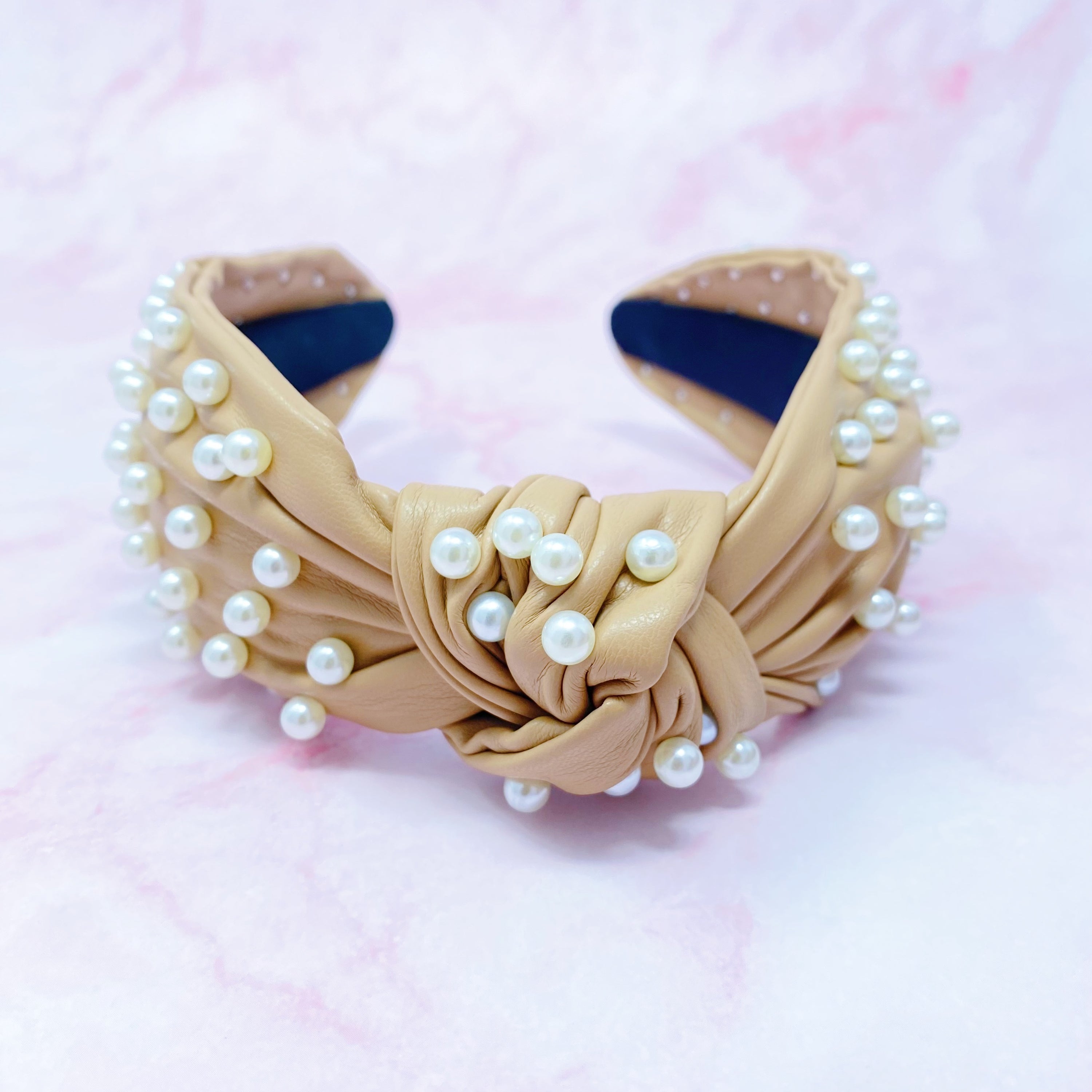 A stylish Pearled Up Vegan Leather Headband featuring soft vegan leather and elegant pearl embellishments in neutral colors.