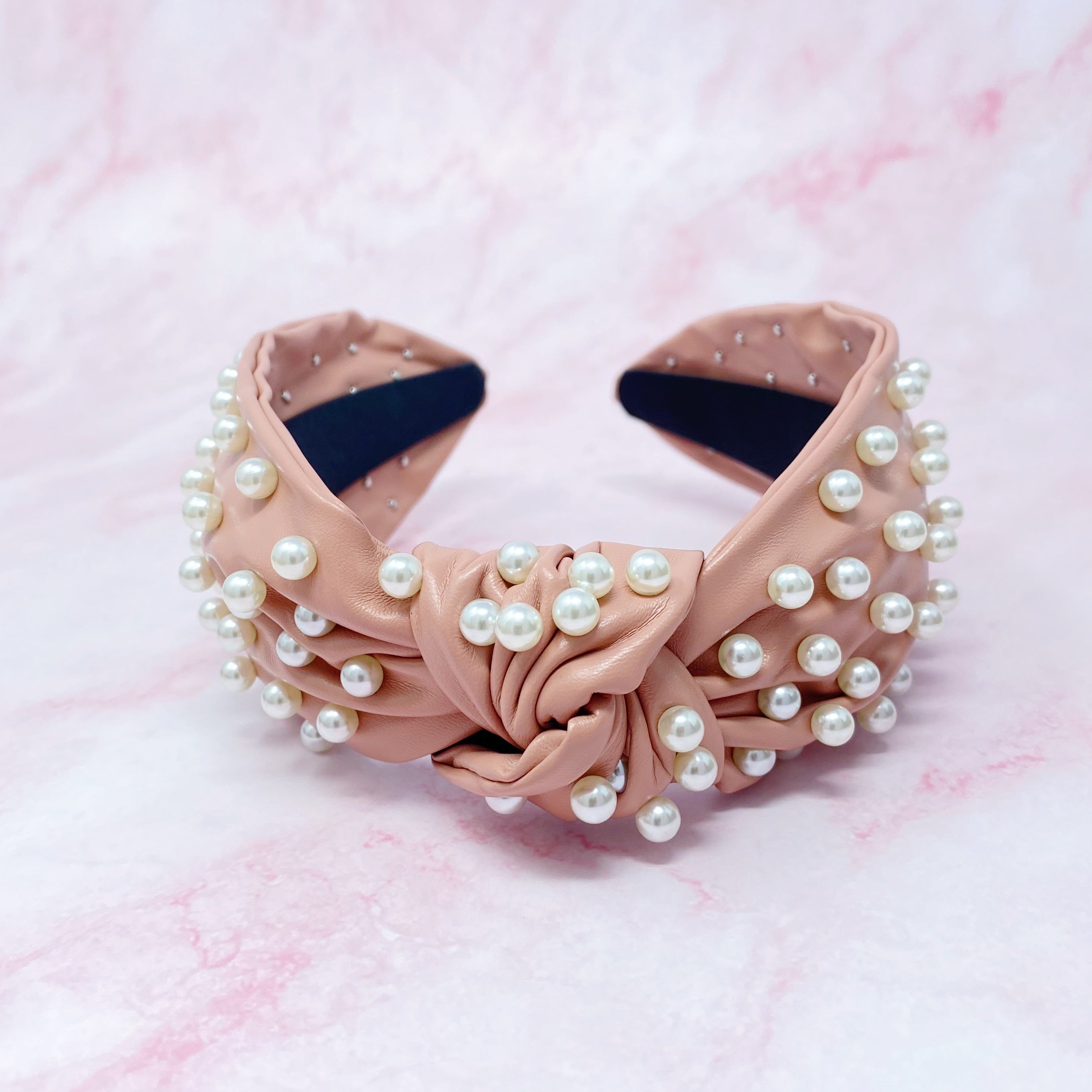 A stylish Pearled Up Vegan Leather Headband featuring soft vegan leather and elegant pearl embellishments in neutral colors.