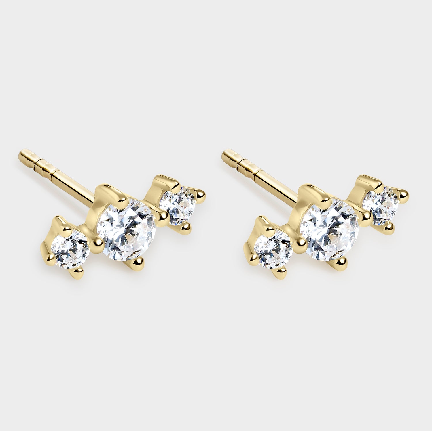 Pendientes elegantes bañados en oro de 18K con tres circonitas blancas engastadas en garras, brillantes y sofisticados.