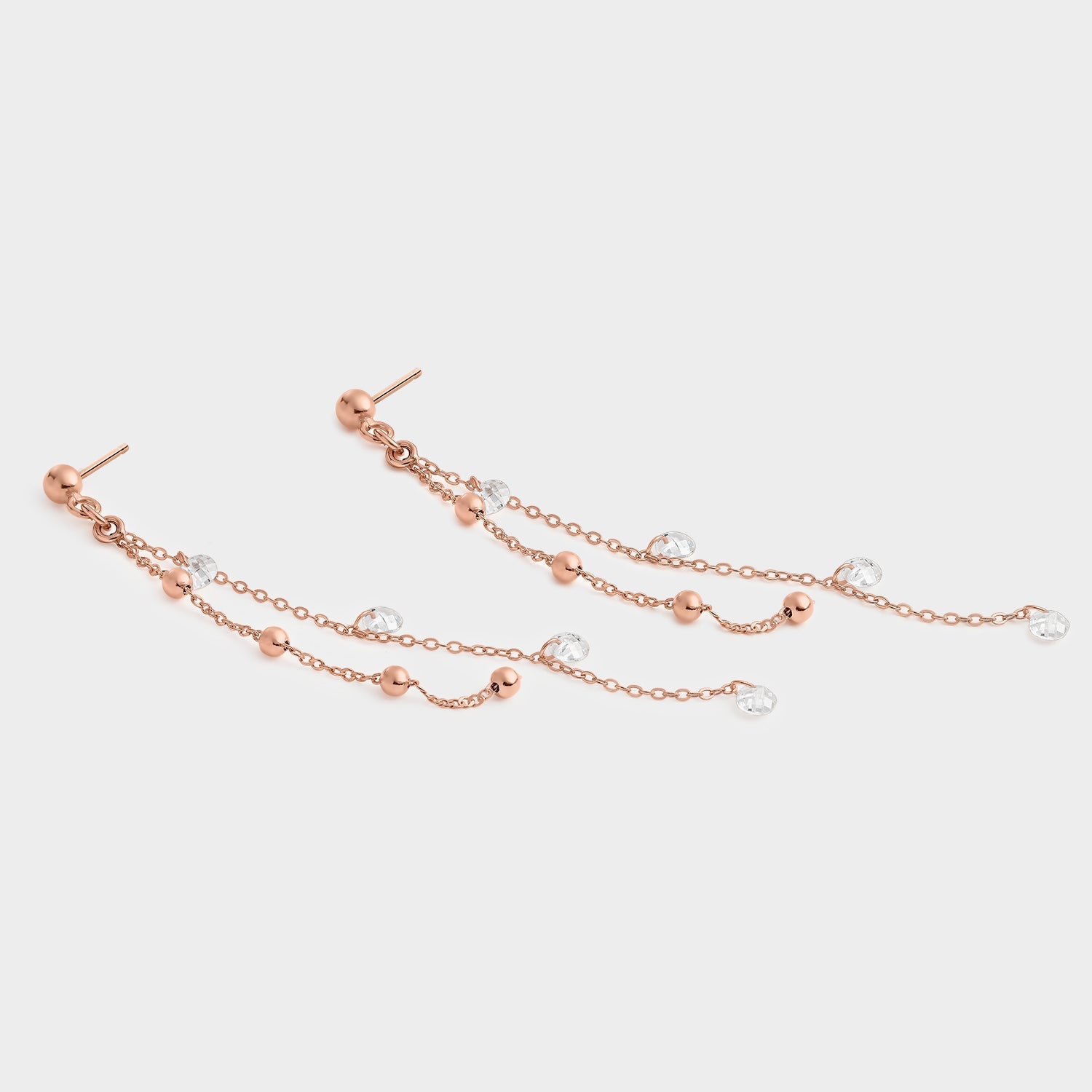 Pendientes de cadenas en oro rosa con circonitas blancas, mostrando su elegante diseño y brillo.
