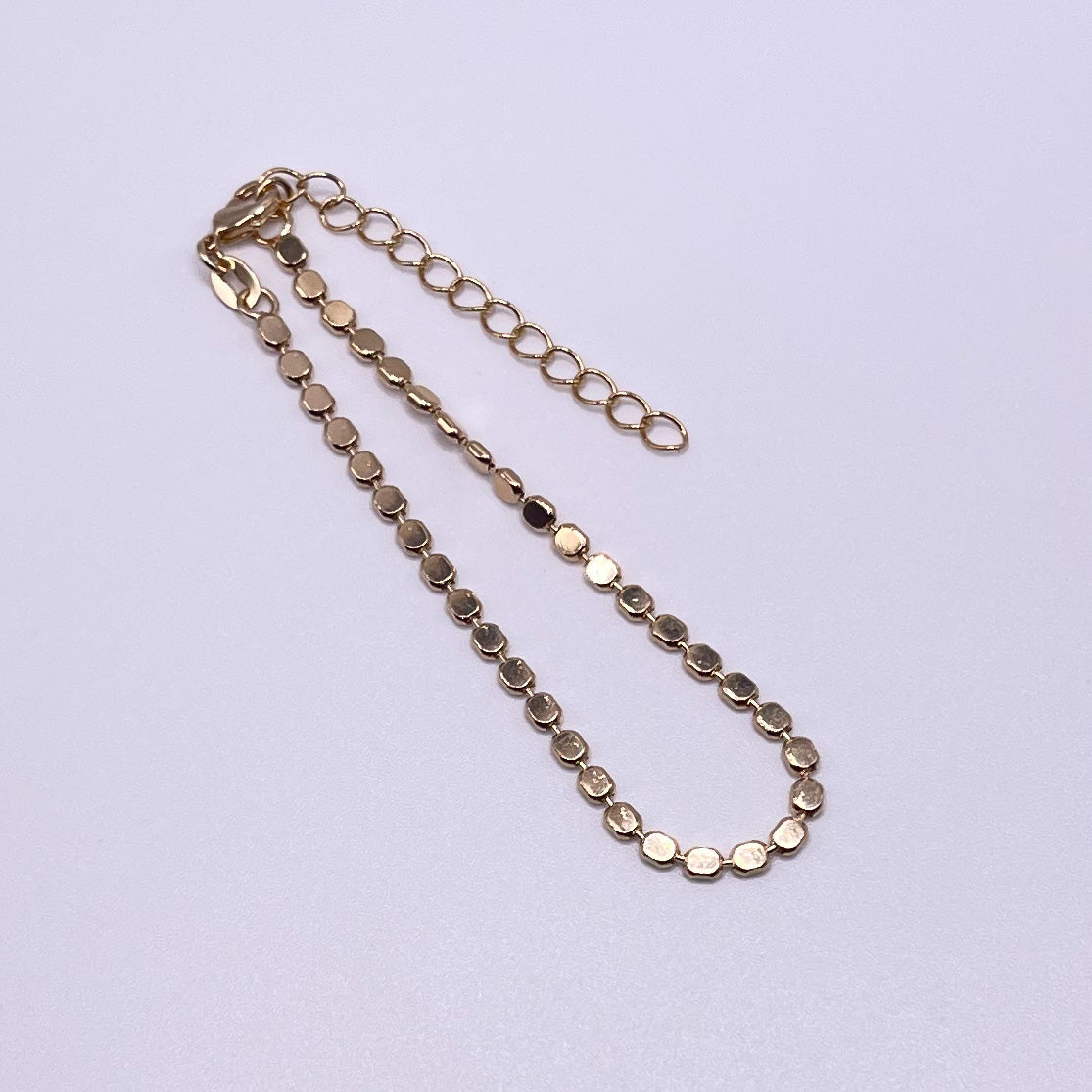Penelope 18K Gold Filled Bracelet/Anklet featuring a dainty flat ball disc design, shining elegantly in light.
