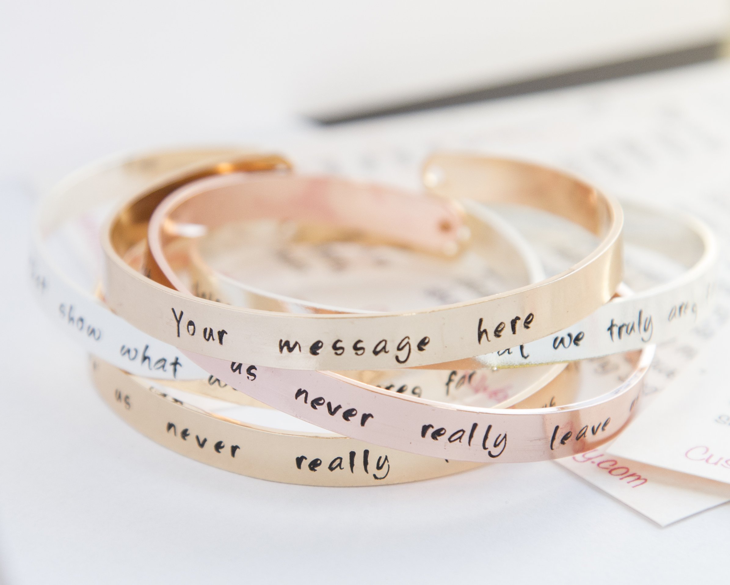 Personalized stamped cuff bracelet in copper with rose gold plating, featuring a custom hand-stamped message.