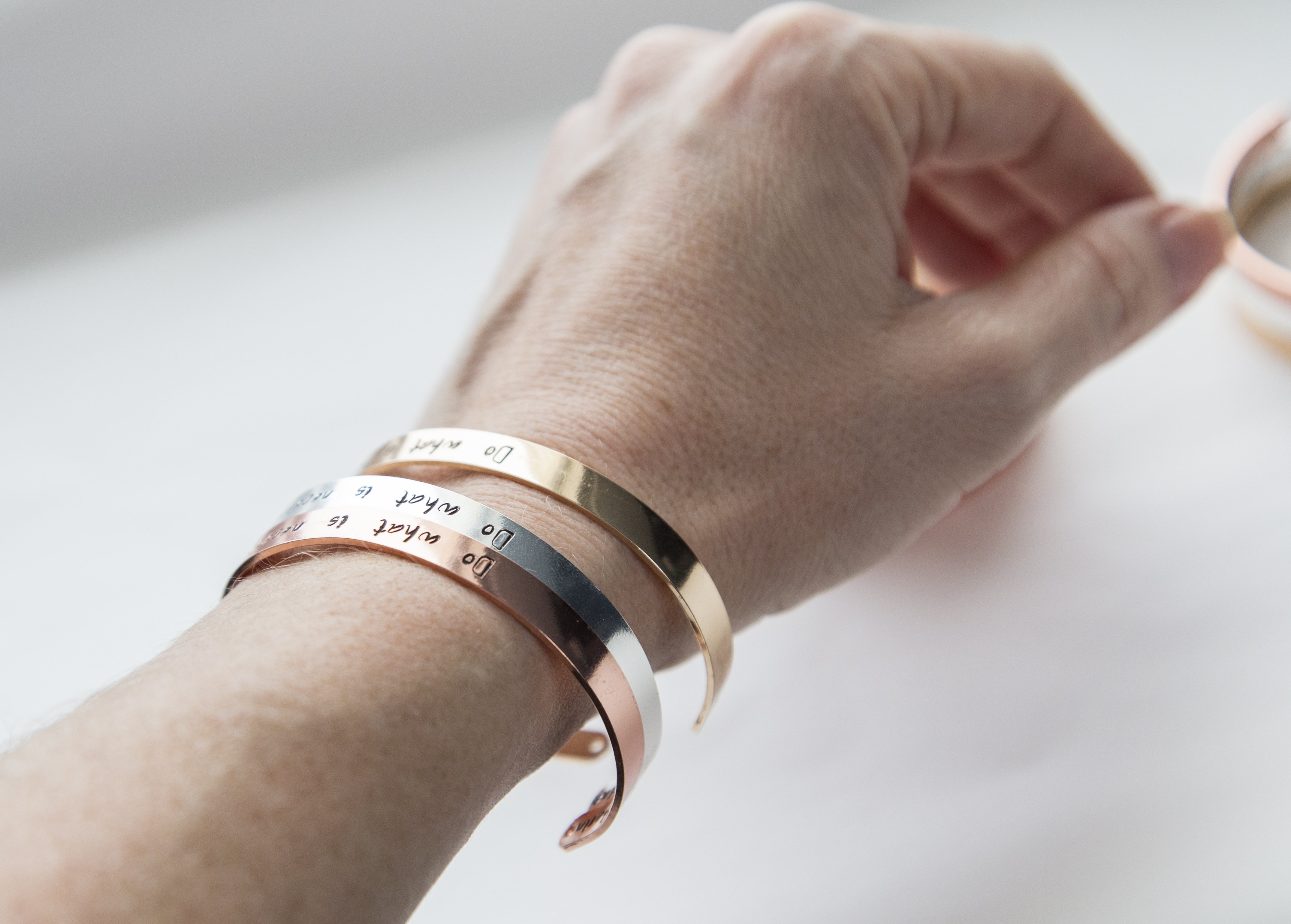 Personalized stamped cuff bracelet in copper with rose gold plating, featuring a custom hand-stamped message.