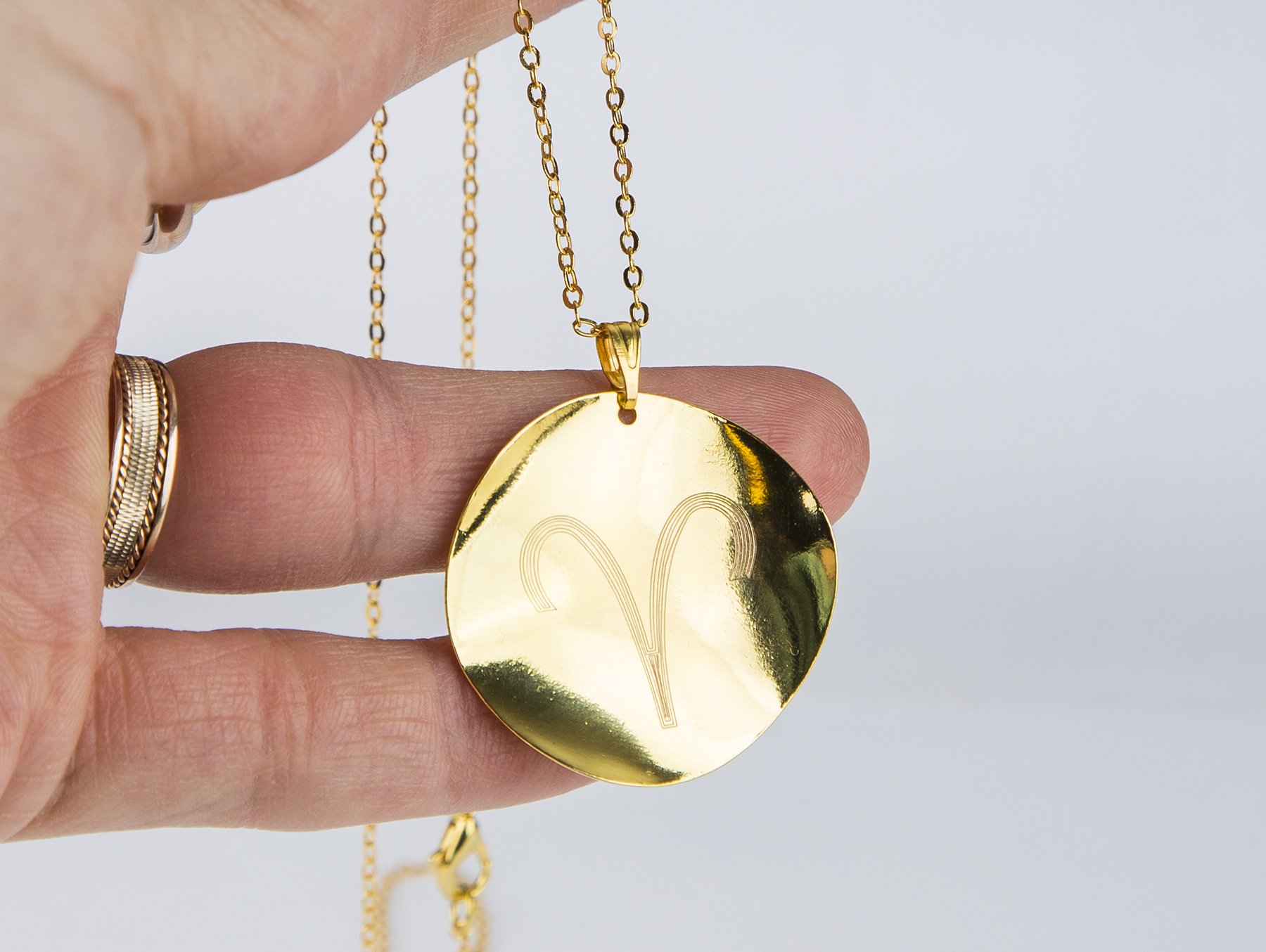 Personalized Zodiac Symbol Pendant in gold plating, featuring a twisted design and attached to a stainless steel necklace.