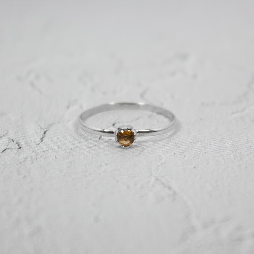 A delicate Petite Citrine Solitaire Ring featuring a round citrine gemstone set in a unique castle setting, crafted from 925 sterling silver.