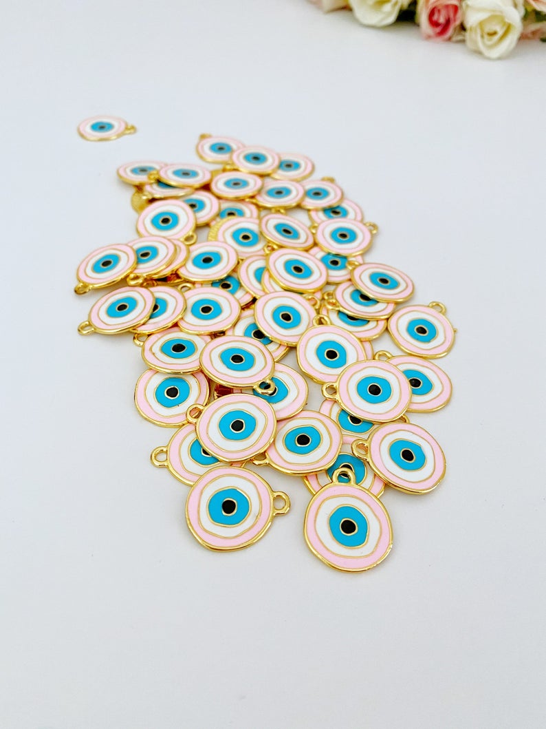 A beautiful pink evil eye charm with gold plating, featuring a traditional evil eye design, perfect for jewelry making.