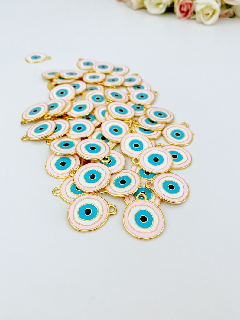 A beautiful pink evil eye charm with gold plating, featuring a traditional evil eye design, perfect for jewelry making.