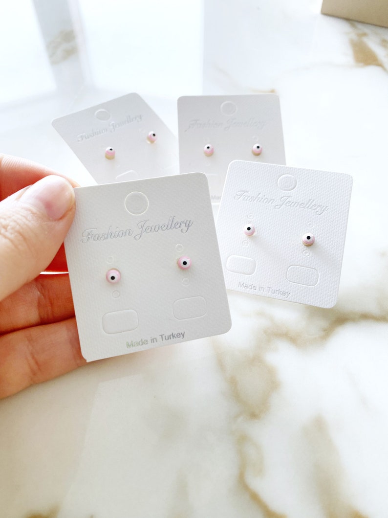 A pair of handmade pink evil eye stud earrings with gold finishing, symbolizing protection and elegance.