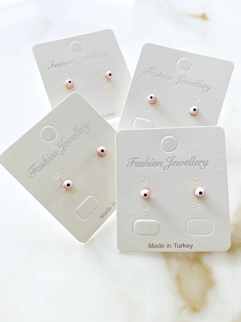 A pair of handmade pink evil eye stud earrings with gold finishing, symbolizing protection and elegance.