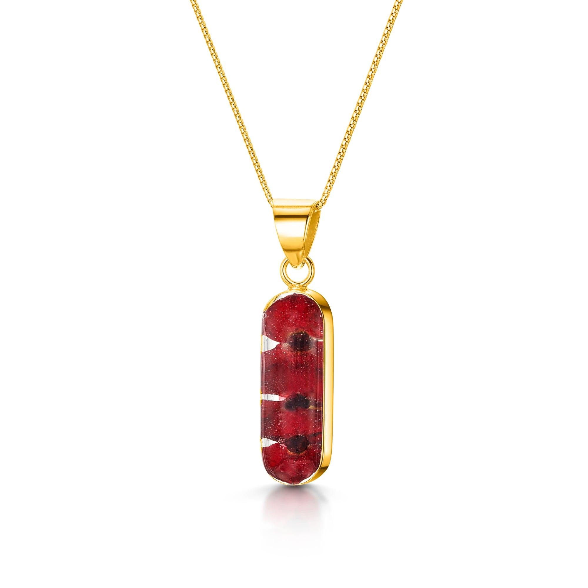 Poppy necklace 'Leela' featuring a vertical bar pendant with tiny red Euphorbia Milii flowers encased in resin, on a sterling silver chain.