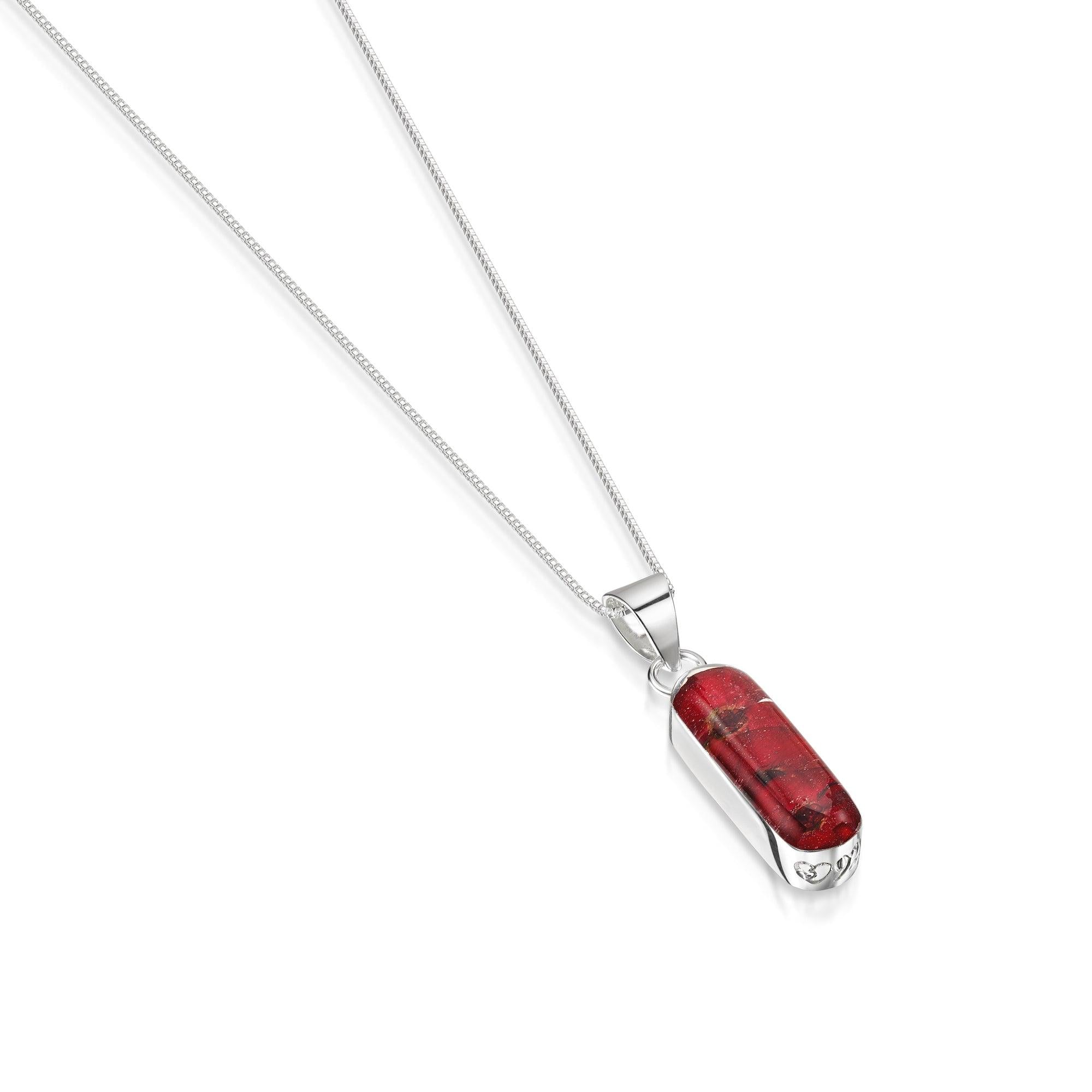 Poppy necklace 'Leela' featuring a vertical bar pendant with tiny red Euphorbia Milii flowers encased in resin, on a sterling silver chain.