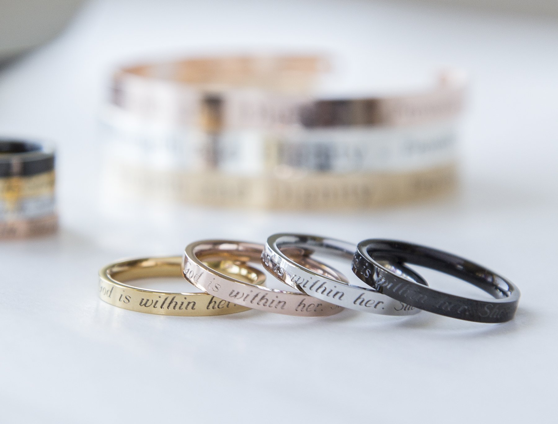 Psalm 46:5 Ring in gold, rose gold, and black plating, engraved with 'God is within her; she will not fail', showcasing its elegant design.