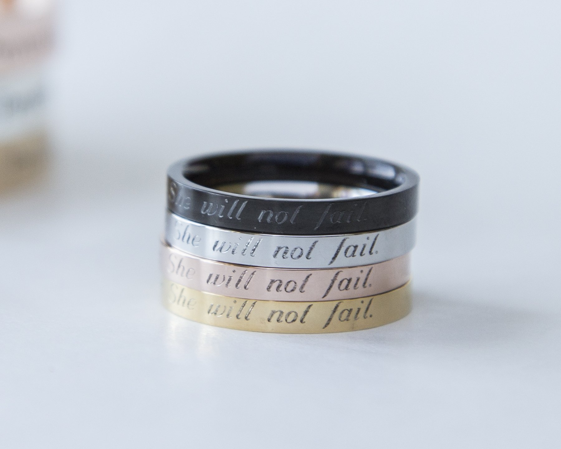 Psalm 46:5 Ring in gold, rose gold, and black plating, engraved with 'God is within her; she will not fail', showcasing its elegant design.