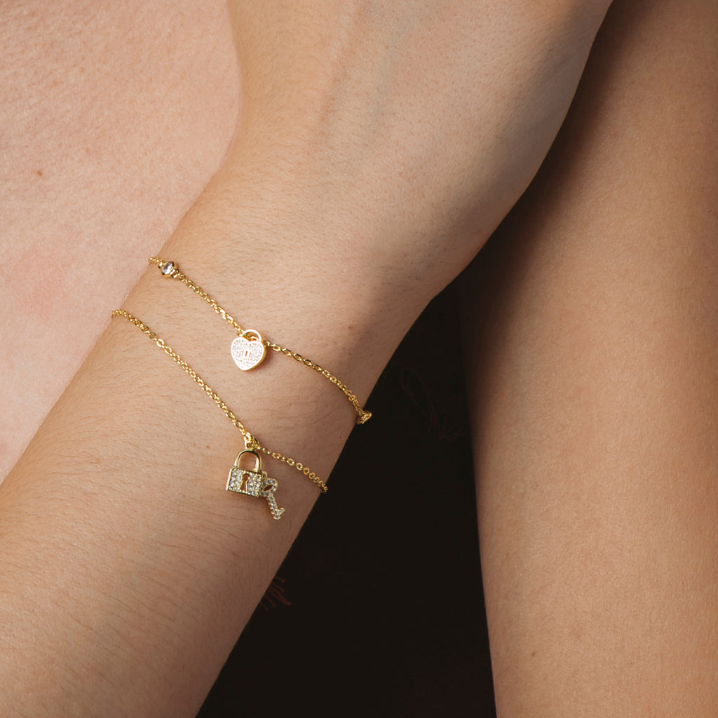 Pulsera elegante bañada en oro amarillo con circonitas blancas, motivos de llave y candado, ajustable y con cierre seguro.