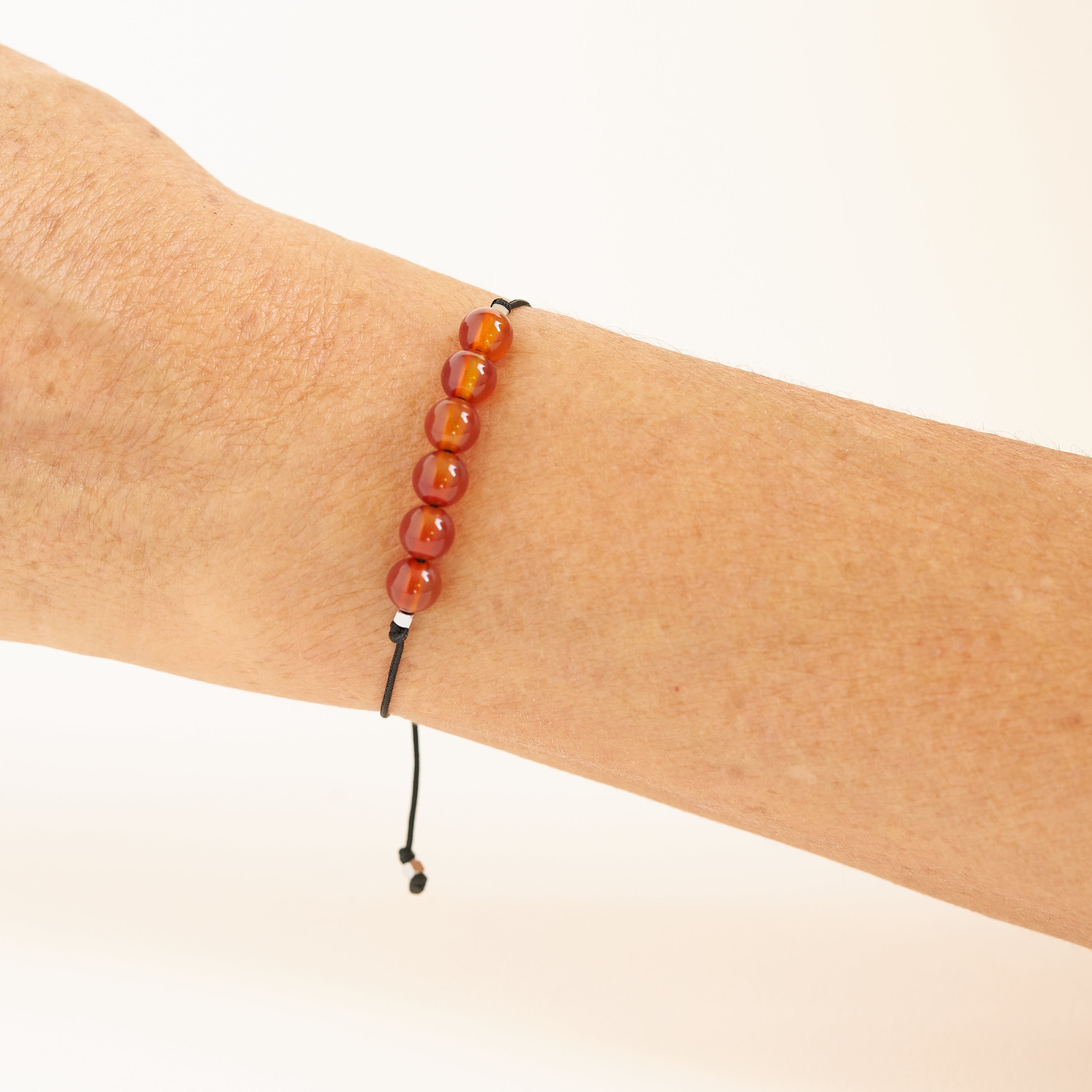 Pulsera de hilo negro con piedras de cornalina roja, ajustable y hecha a mano, ideal como regalo de cumpleaños para el mes de Julio.