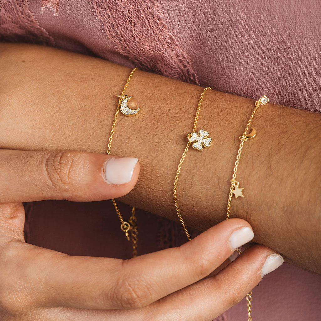 Pulsera de plata bañada en oro con colgantes de lunas y estrellas, adornada con circonitas blancas brillantes.