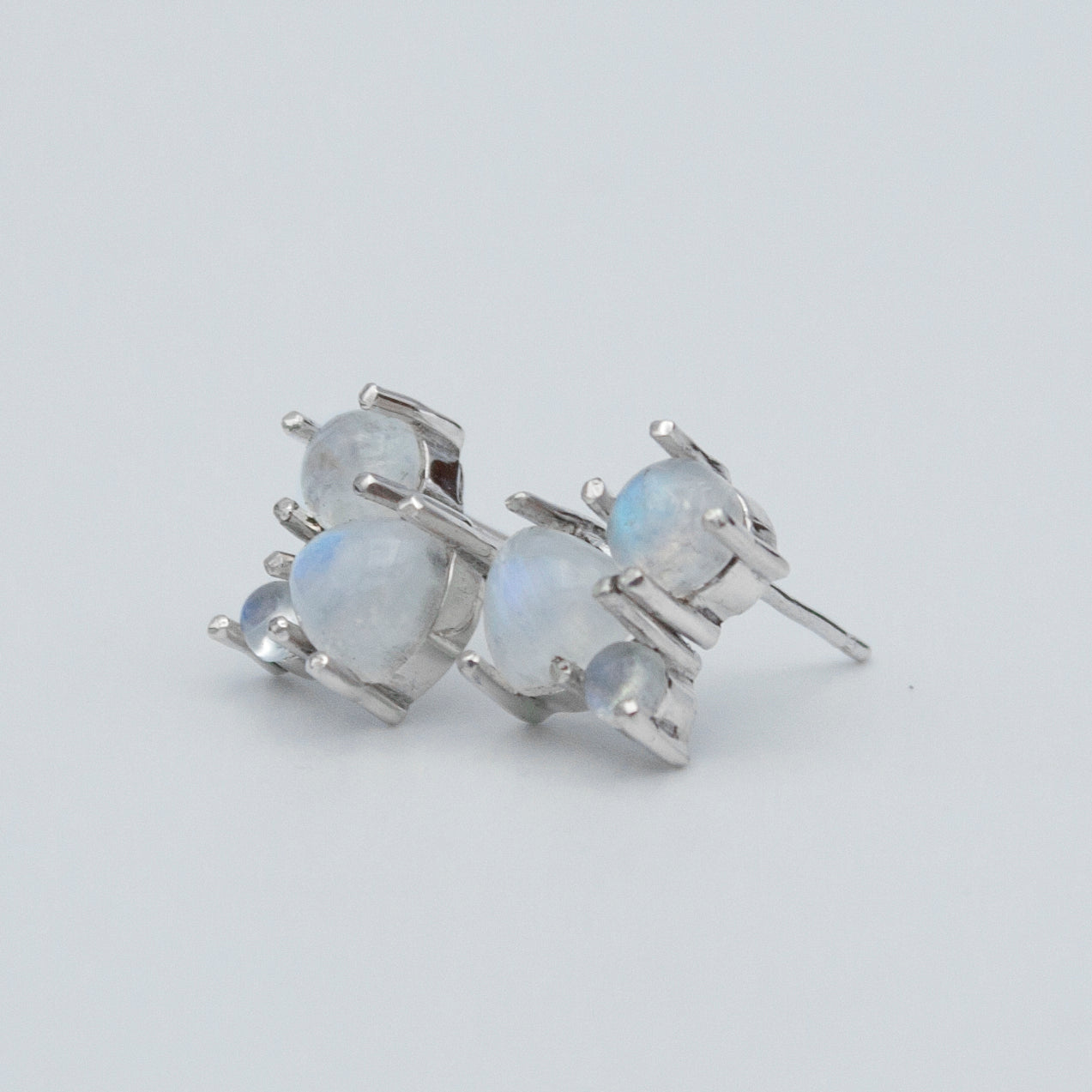 A pair of elegant Rainbow Moonstone Cluster Sterling Silver Earrings featuring round and trillion cut gemstones set in .925 sterling silver.