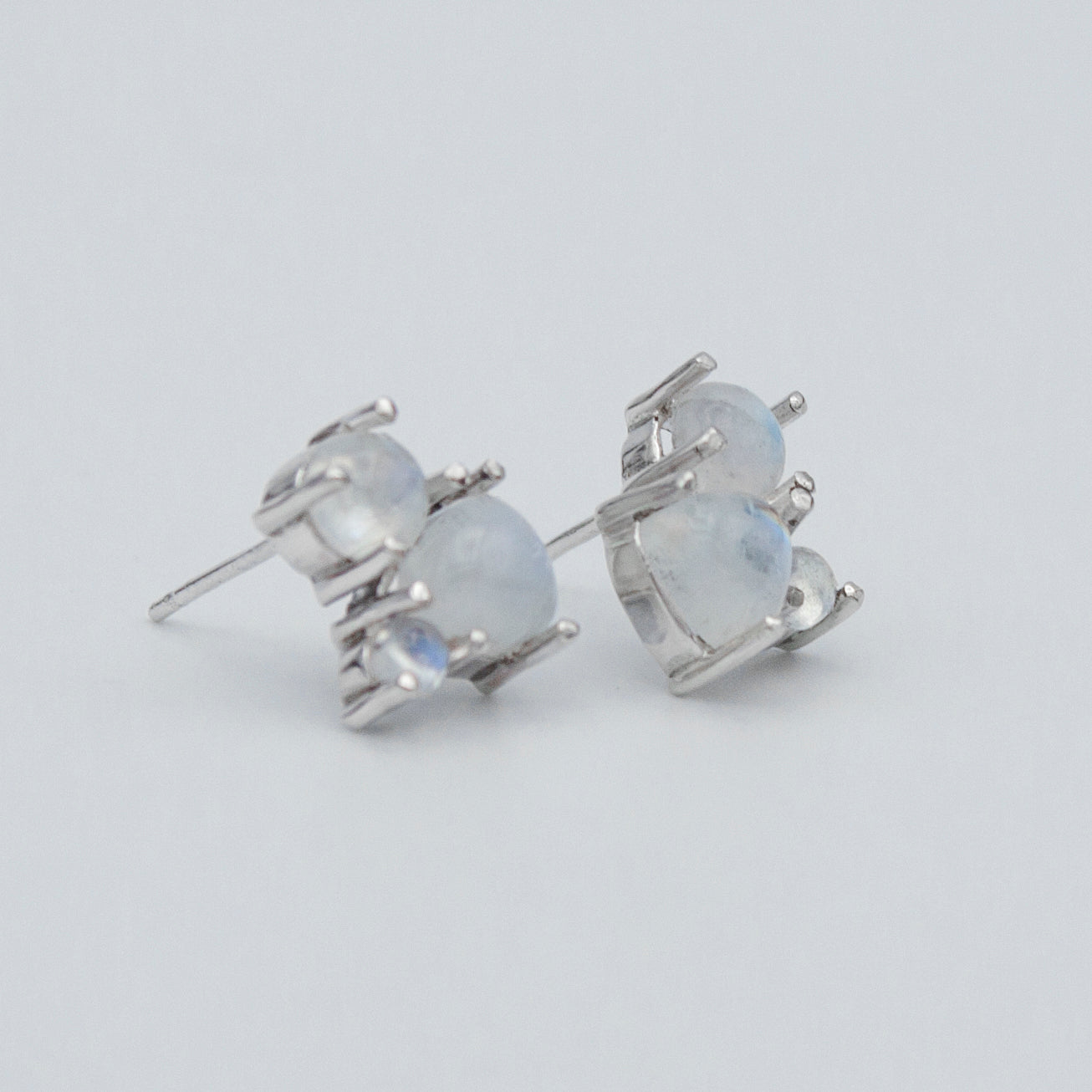 A pair of elegant Rainbow Moonstone Cluster Sterling Silver Earrings featuring round and trillion cut gemstones set in .925 sterling silver.