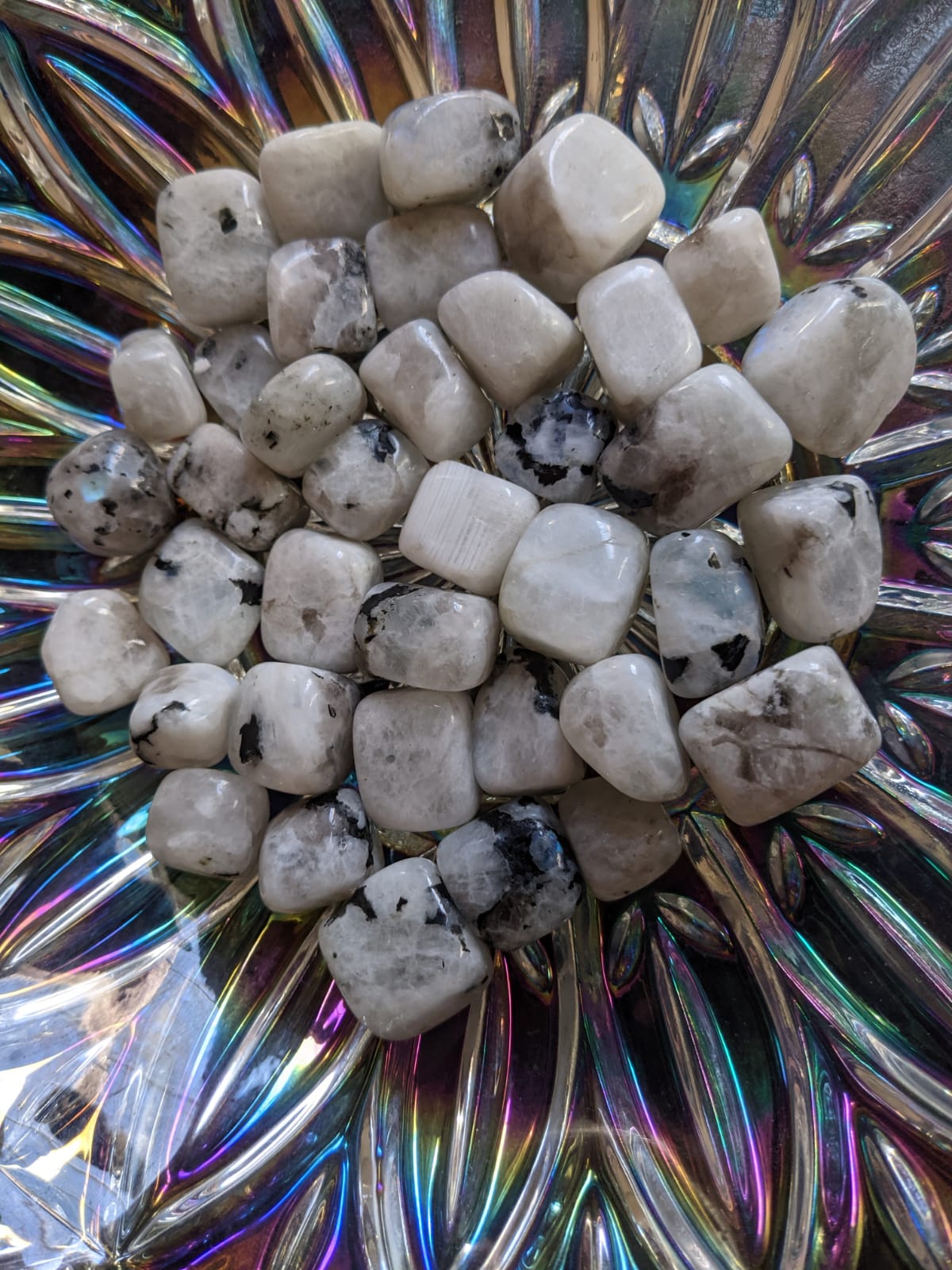 A collection of polished Rainbow Moonstone Tumbled Stones showcasing their iridescent colors and smooth surfaces.