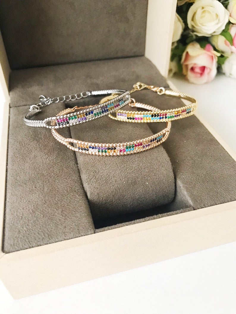 Rainbow Zircon Bangle Bracelet featuring turquoise beads and a movable evil eye charm in rose gold and silver finishes.