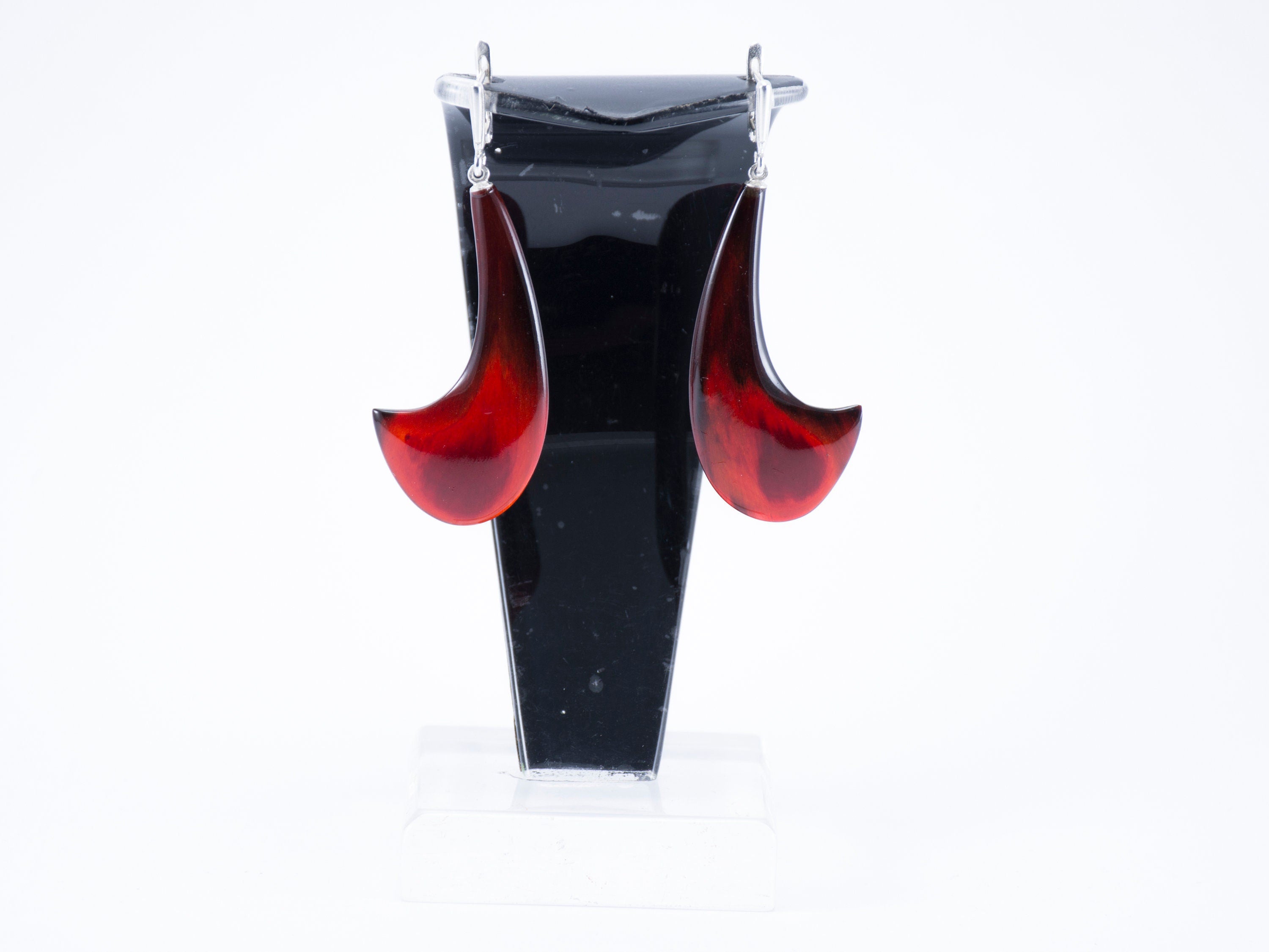 A pair of handmade red buffalo horn earrings featuring a shiny polished surface and geometric column shape, secured with silver English locks.