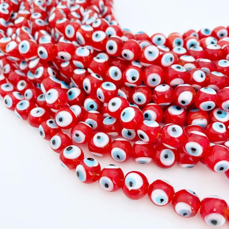 A close-up view of shiny red 12mm glass evil eye beads, showcasing their vibrant color and round shape, perfect for jewelry making.