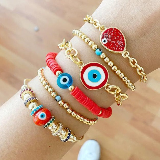 A beautifully crafted Red Evil Eye Bracelet set featuring red evil eye beads, Pandora charms, and gold stretchable design, showcasing its handmade quality.