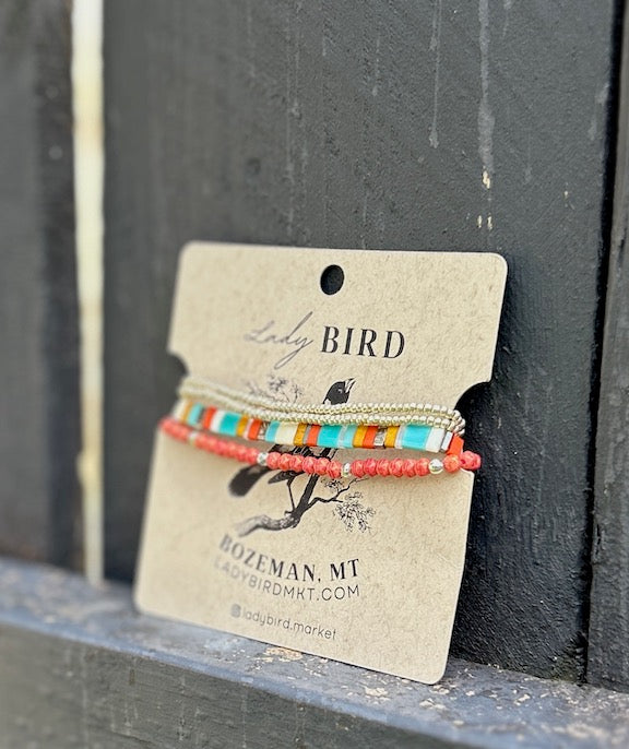 A vibrant stacked wrap bracelet set featuring turquoise Tila beads with retro stripes in orange, yellow, and silver or gold, showcasing a bohemian style.