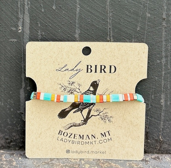 A vibrant stacked wrap bracelet set featuring turquoise Tila beads with retro stripes in orange, yellow, and silver or gold, showcasing a bohemian style.