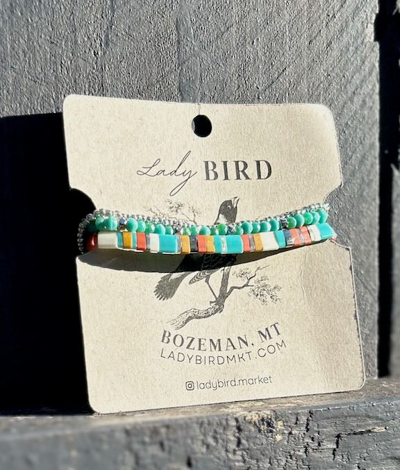 A vibrant stacked wrap bracelet set featuring turquoise Tila beads with retro stripes in orange, yellow, and silver or gold, showcasing a bohemian style.