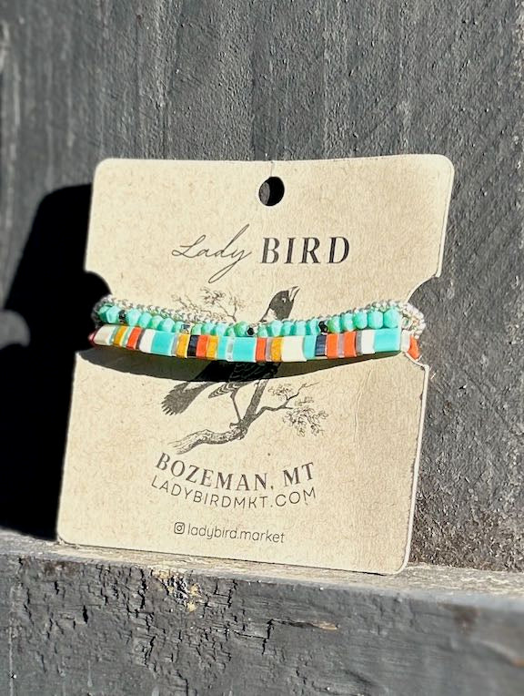 A vibrant stacked wrap bracelet set featuring turquoise Tila beads with retro stripes in orange, yellow, and silver or gold, showcasing a bohemian style.